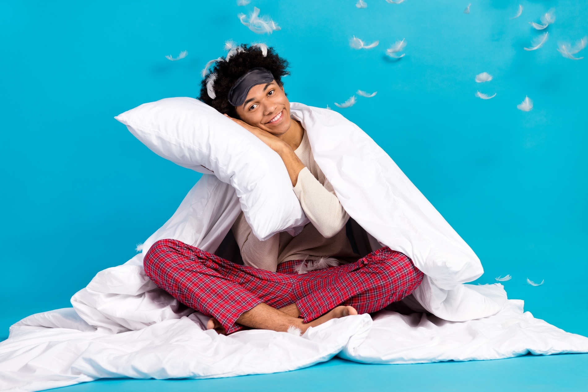 Ein Mann, der sitzend im Bett kuschelt, symbolisiert eine angenehme Zahnreinigung.